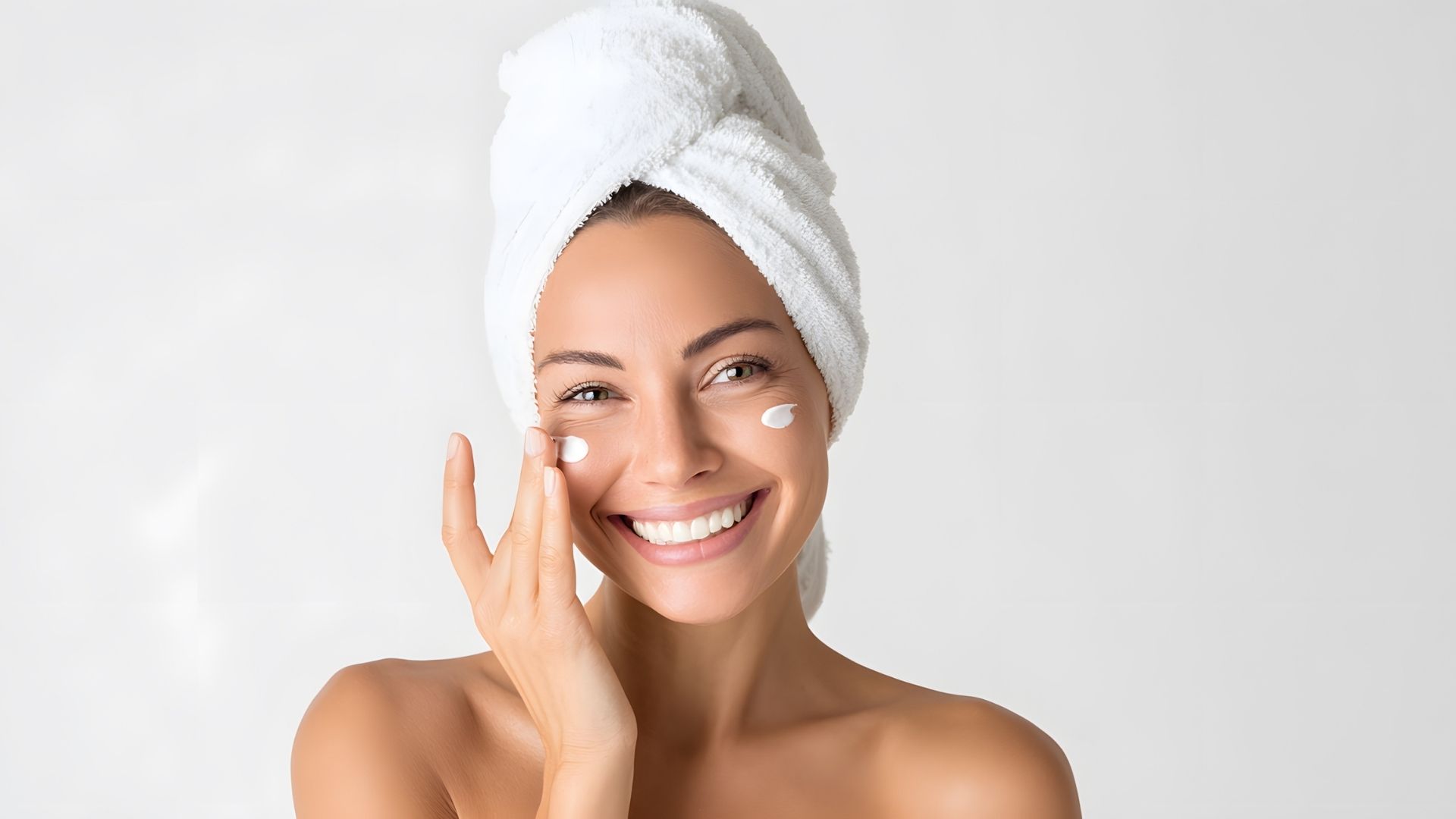 Uśmiechnięta kobieta nakłada regenerujący krem na twarz – pielęgnacja cery z uszkodzoną barierą hydrolipidową produktami Manilu